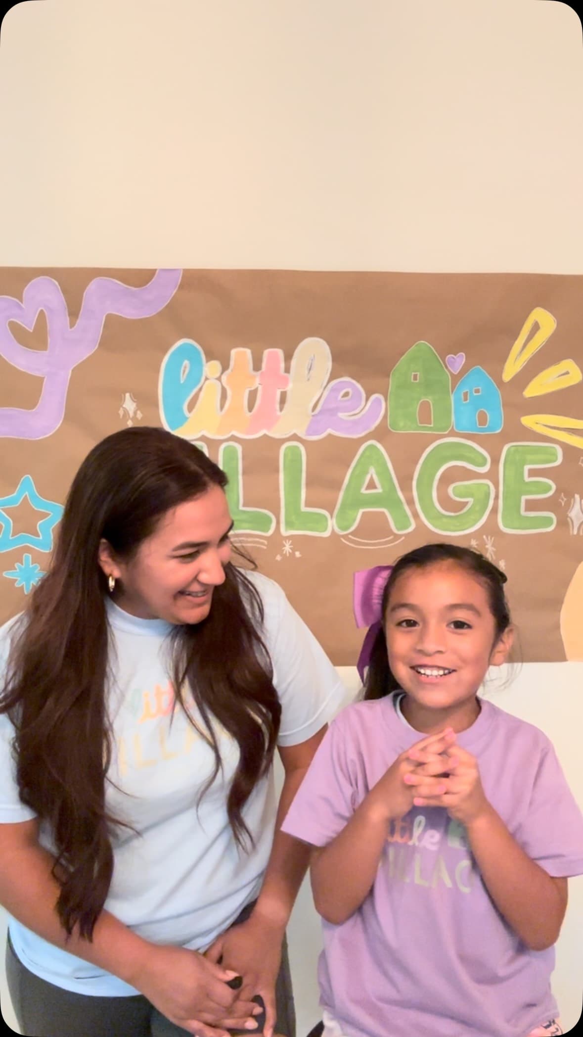A woman standing next to a little girl in front of a sign.